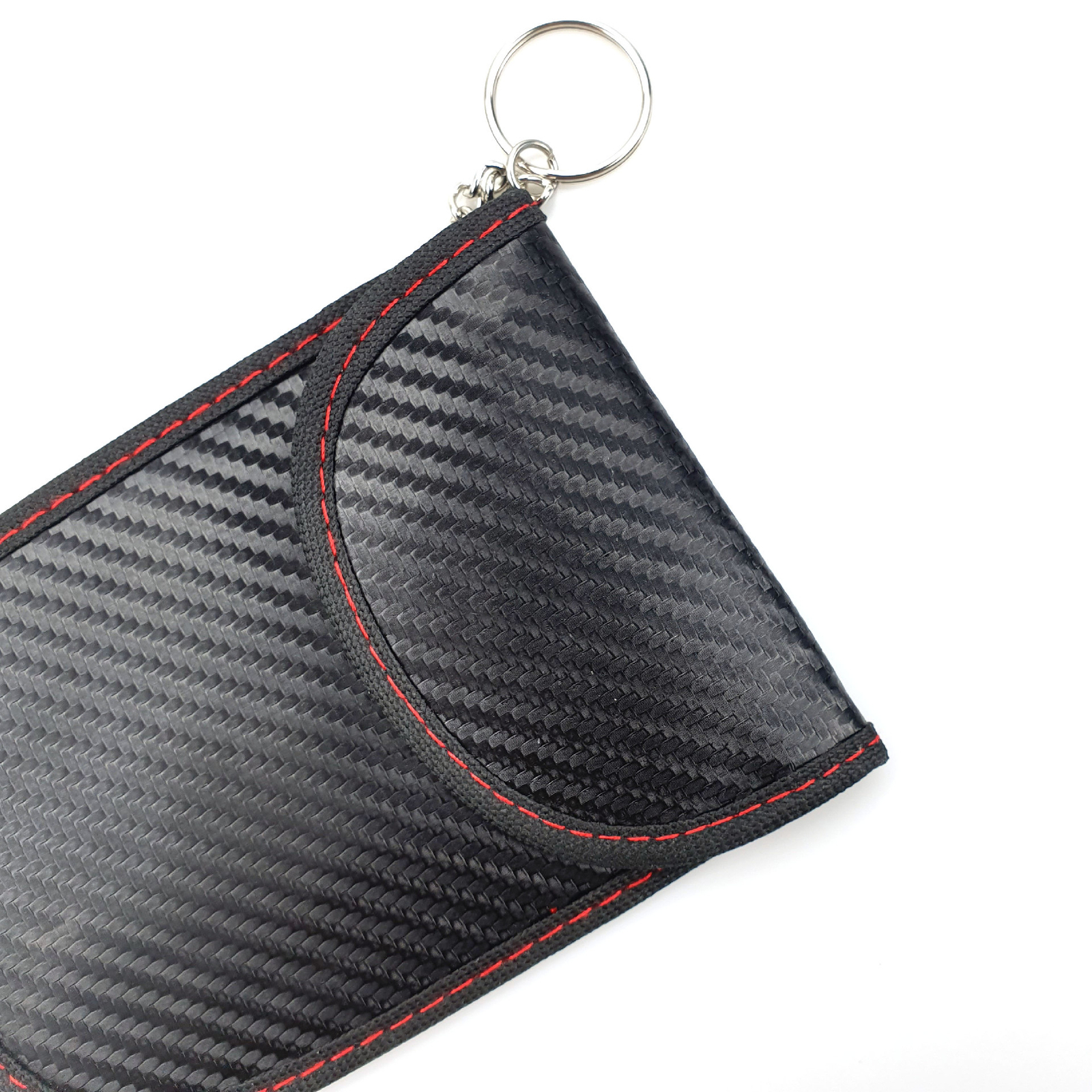Primer plano de la textura de fibra de carbono, las costuras rojas, el borde reforzado y la anilla metálica de una bolsa de bloqueo RFID.