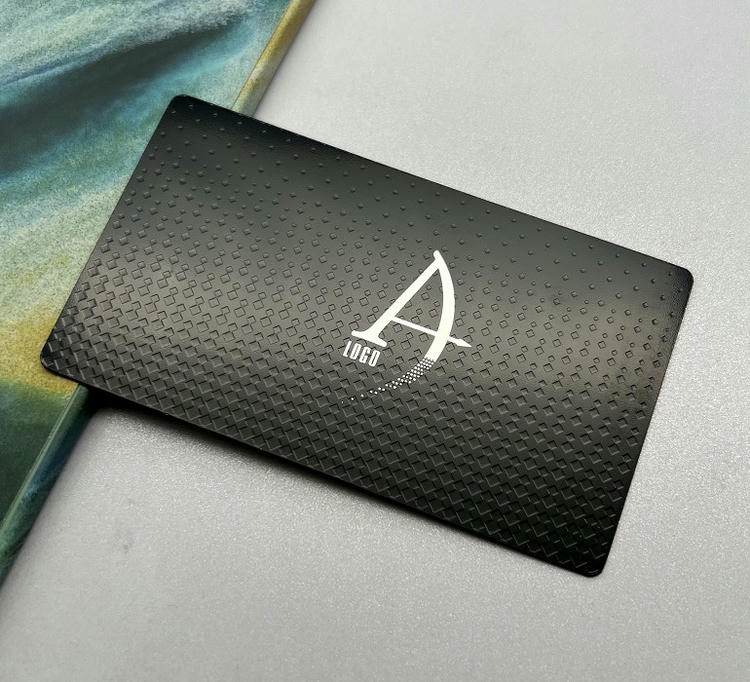 Tarjeta de visita metálica con textura negra y logotipo tipo monograma para una imagen de marca moderna y premium.