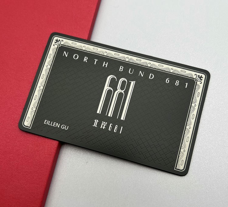 Tarjeta de visita metálica con marco de estilo vintage, logotipo centrado y un fondo oscuro texturizado de aspecto premium.