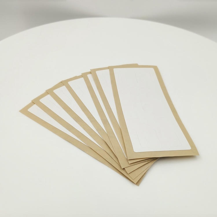 Varias piezas de etiquetas RFID para parabrisas con respaldo kraft se extienden sobre una mesa blanca mostrando los forros empaquetados para su fácil distribución.