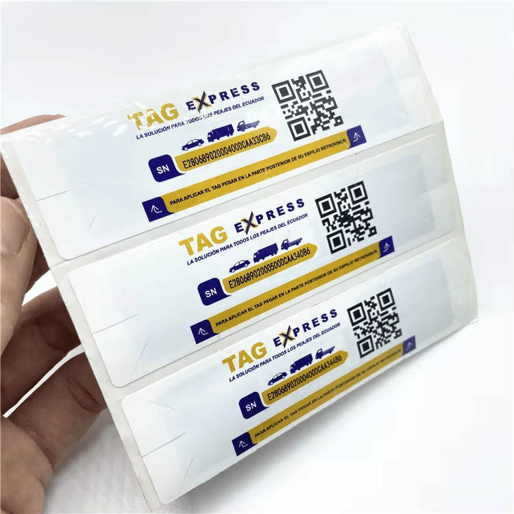 Vista en ángulo de tres etiquetas RFID UHF para parabrisas en una tira, con película protectora transparente e identificadores impresos.