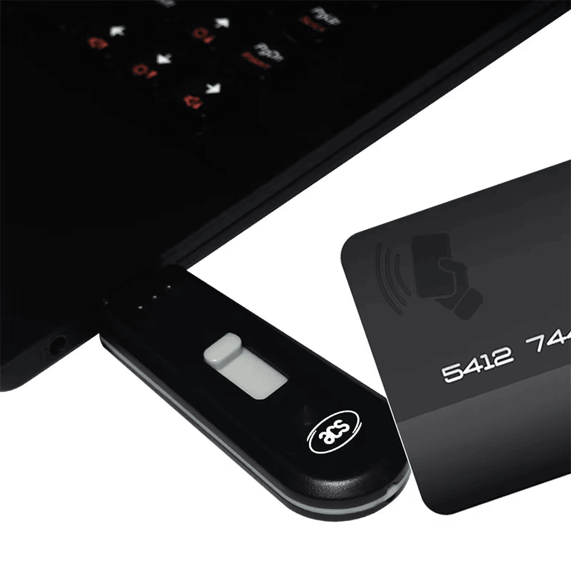 El lector NFC tipo token ACR1251T está conectado a un ordenador portátil junto a una tarjeta bancaria sin contacto para representar un proceso de autenticación segura.